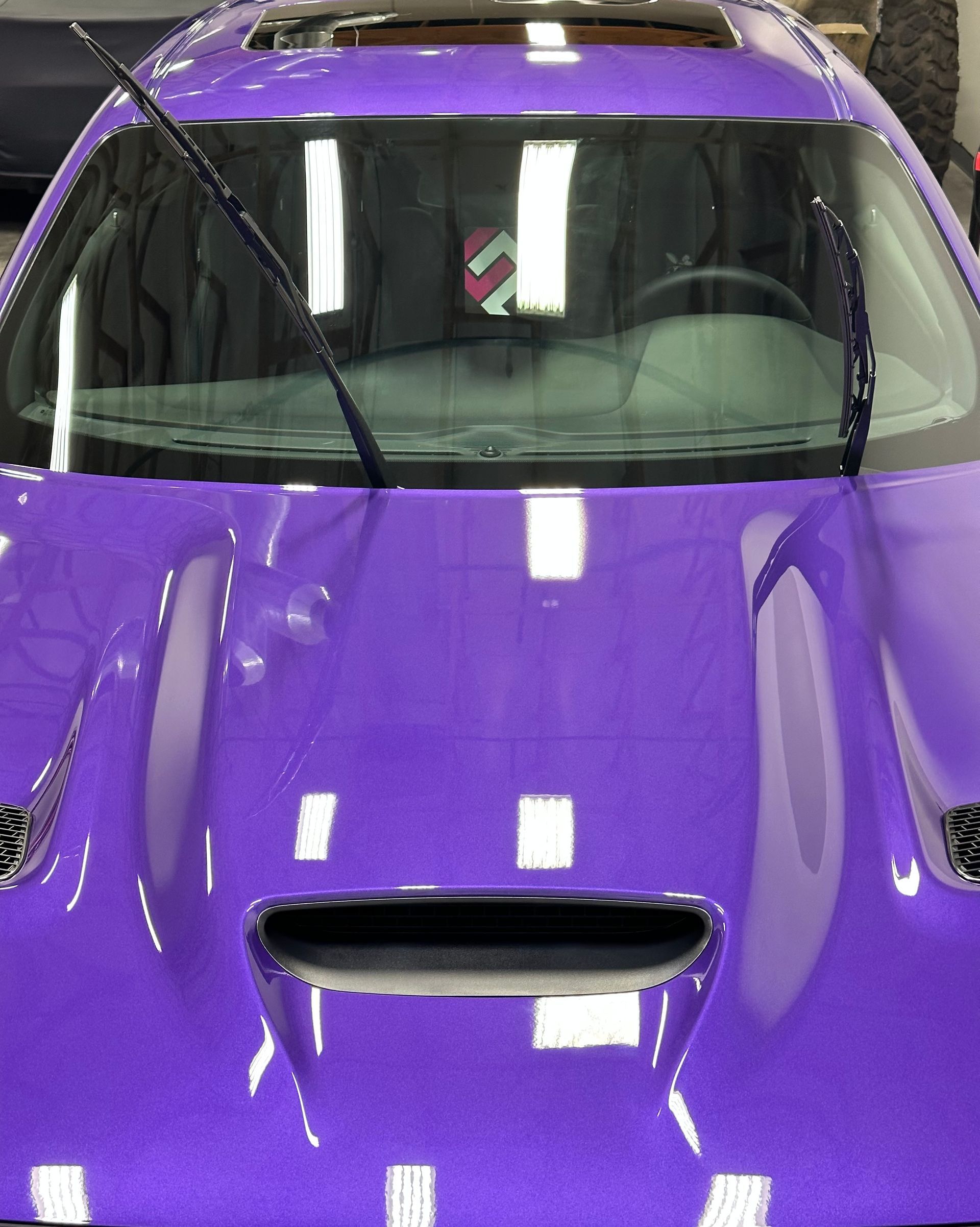 A person is polishing the hood of a blue car.