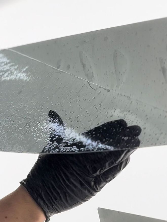 A person is applying a clear film to the hood of a car.