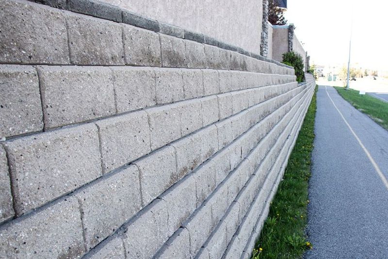 A Brick Wall Is Along The Side Of A Road — DCK Concreting In Lake Cathie, NSW