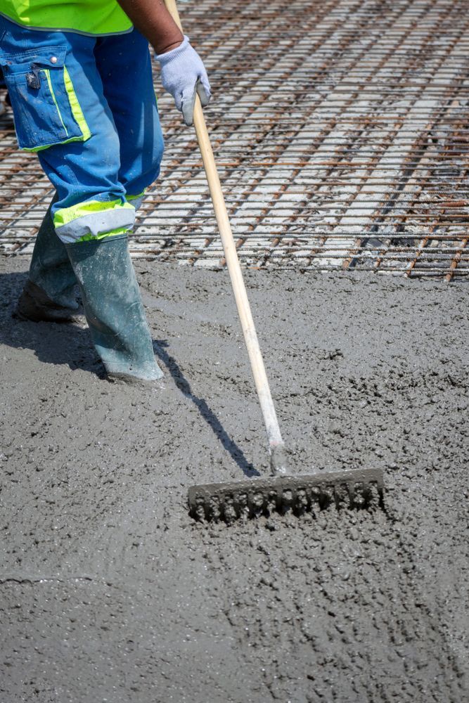 A Construction Worker Is Raking Concrete With A Rake — DCK Concreting In Lake Cathie, NSW