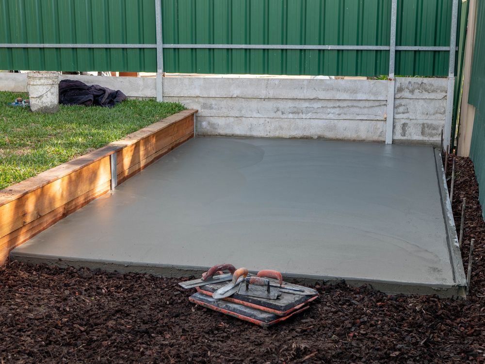 A Concrete Floor Is Being Built In A Backyard Next To A Green Fence — DCK Concreting In Lake Cathie, NSW