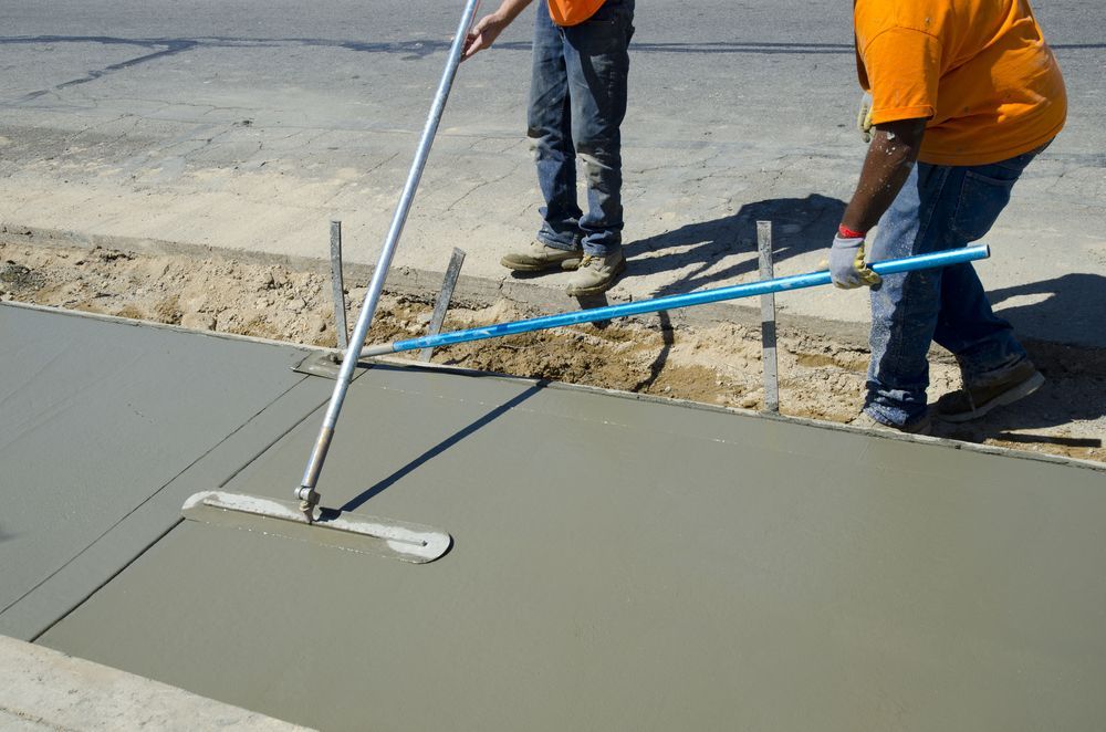 Two Men Are Working On A Sidewalk With A Broom — DCK Concreting In Lake Cathie, NSW