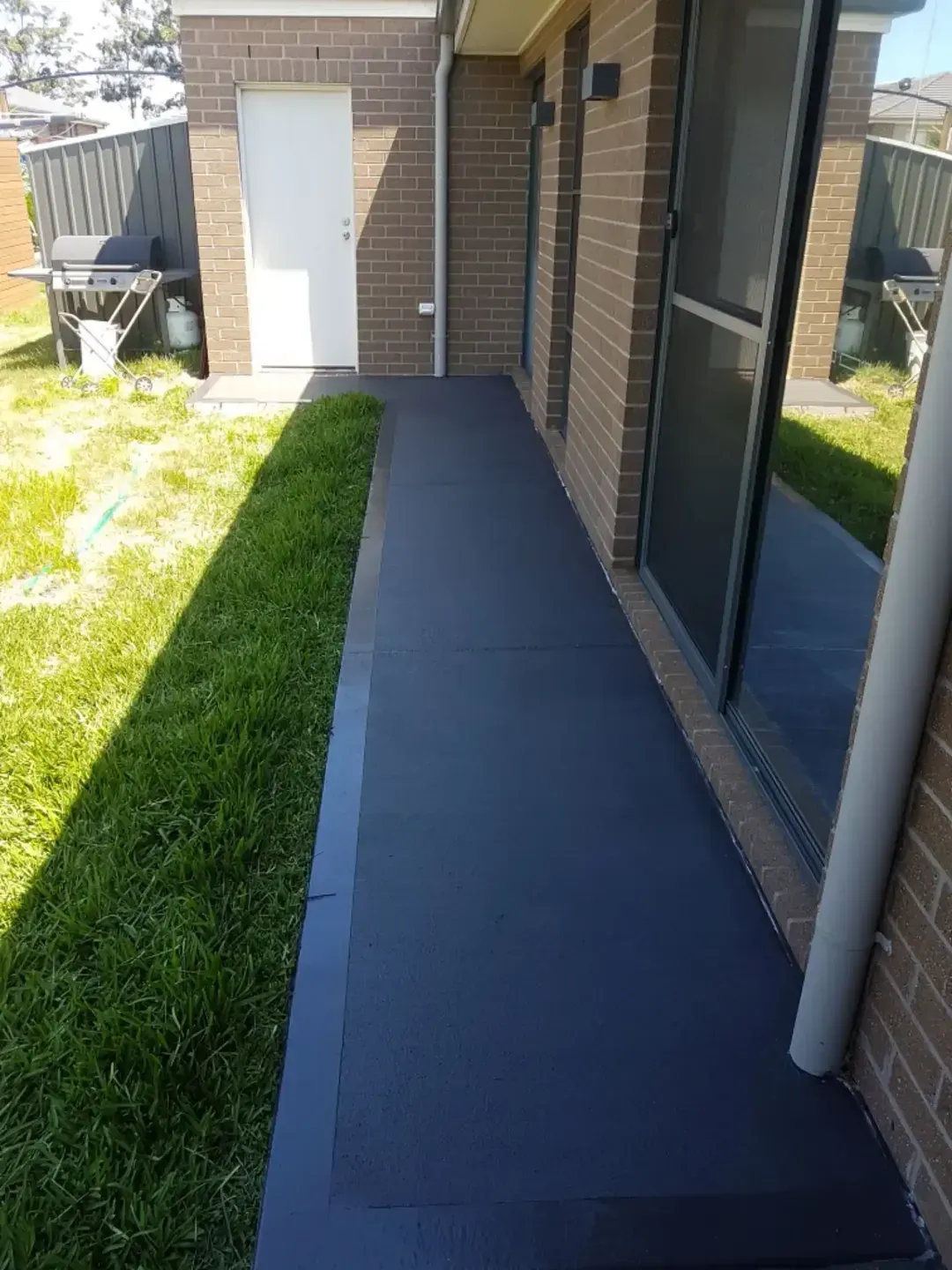 A Brick House With A Walkway Leading To The Backyard — DCK Concreting In Port Macquarie, NSW