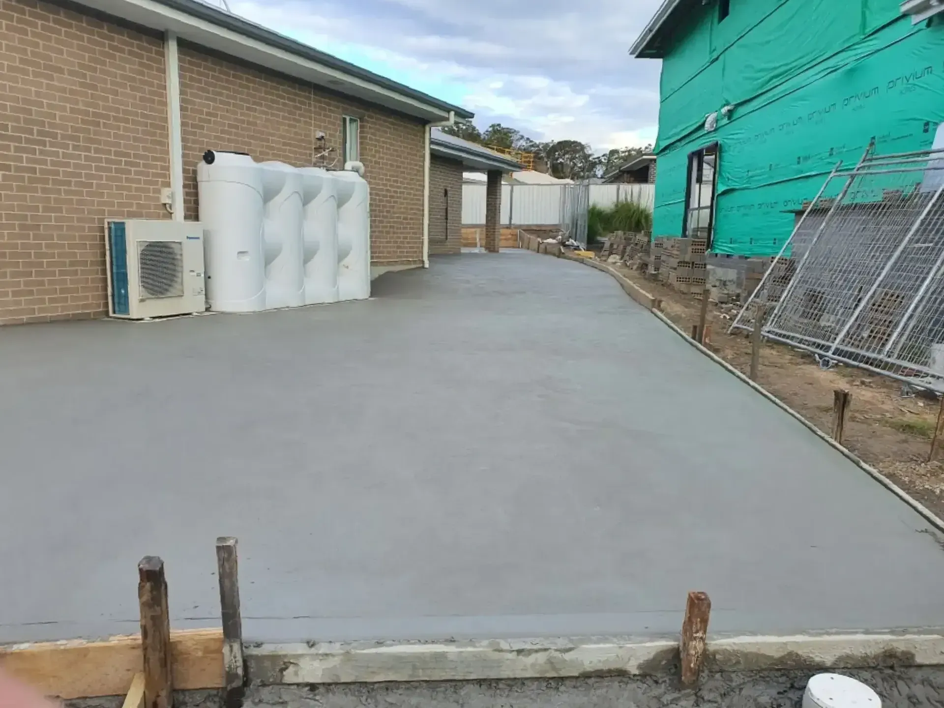 A Concrete Driveway Is Being Built In Front Of A Brick Building — DCK Concreting In Laurieton, NSW