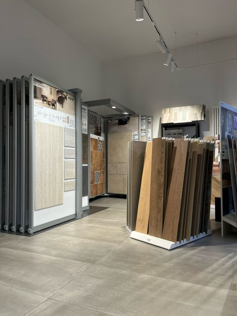 Interno di uno showroom di piastrelle e pavimenti, in cui sono esposti vari campioni di piastrelle e pavimenti in legno.