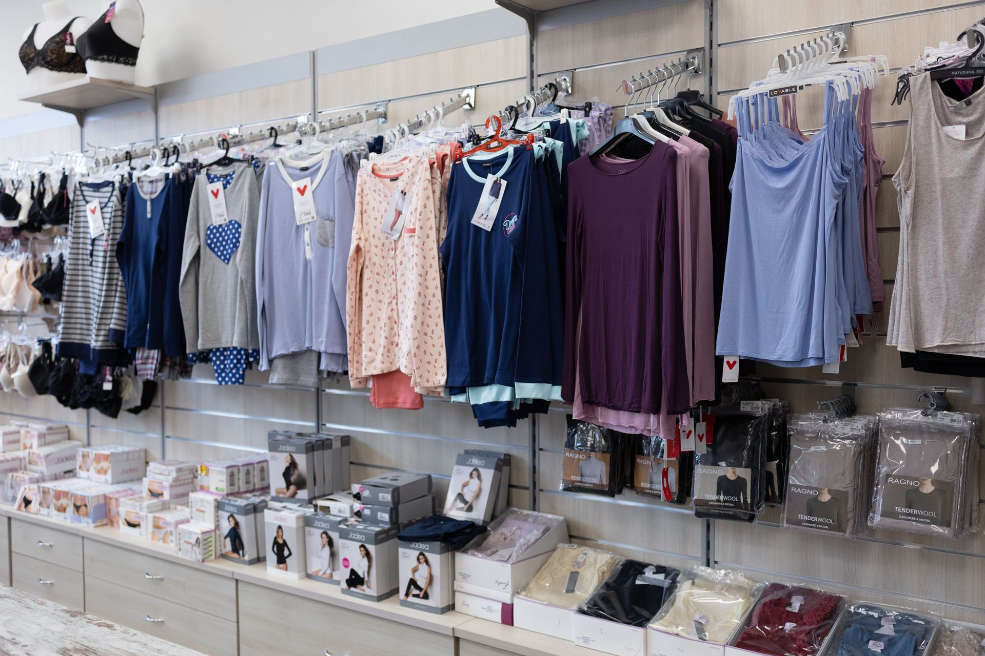 Esposizione di un negozio di abbigliamento con pigiami, top e lingerie su scaffali e scaffali.