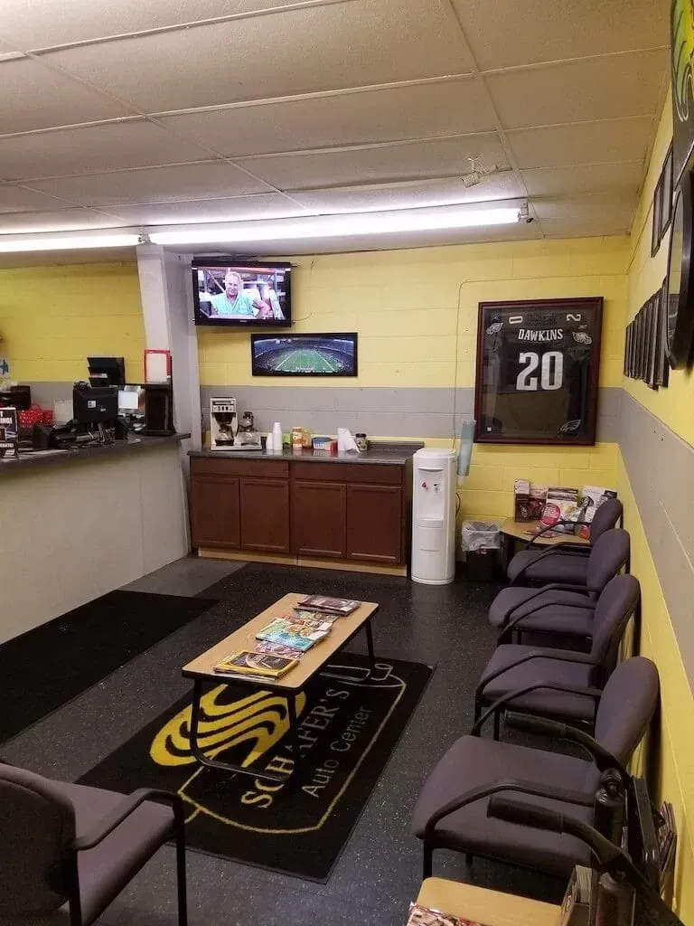 Waiting area with chairs, TV, coffee table, and sports memorabilia on yellow walls.