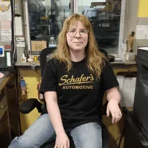 Person seated in an office chair at Schaefer’s Automotive, wearing a black T-shirt and jeans