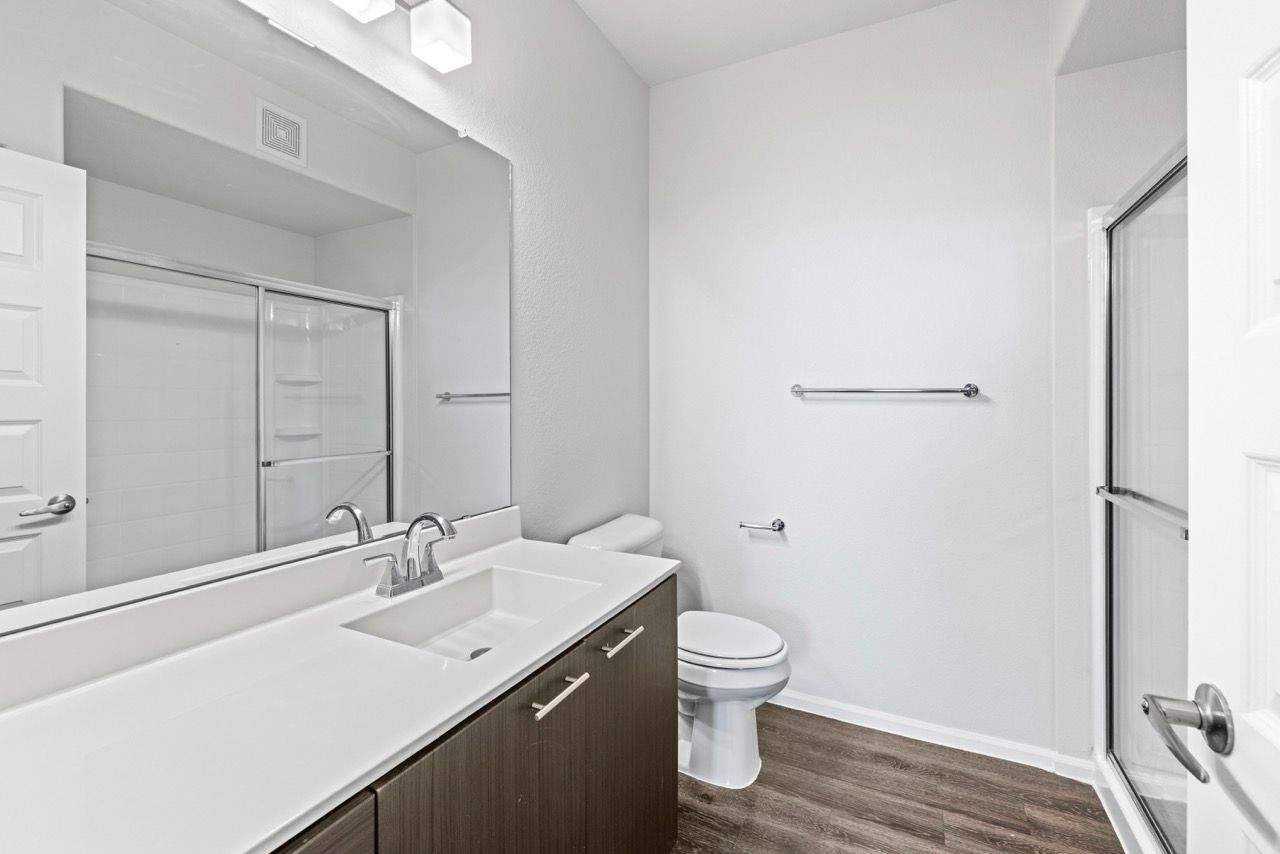 Bathroom in an apartment with a vanity, toilet, and shower.