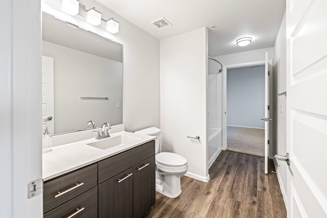 Bathroom with a single-sink vanity, toilet, and bathtub/shower in a modern apartment.