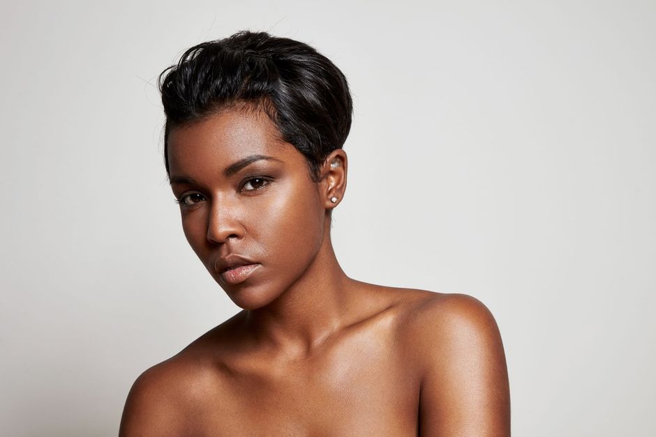 Portrait of a person with short dark hair against a light gray background, looking at the camera with a calm expression
