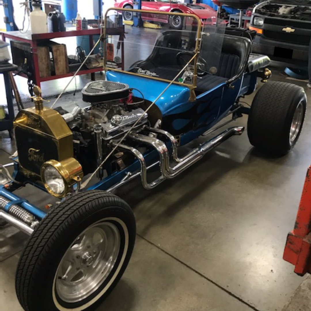 Blue hot rod with chrome details in a garage.