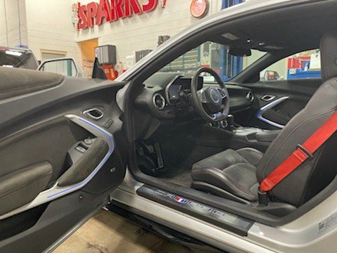 Silver Camaro interior with black and red seats, open door.
