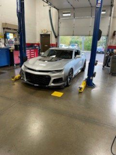 Silver sports car on a lift in a garage.