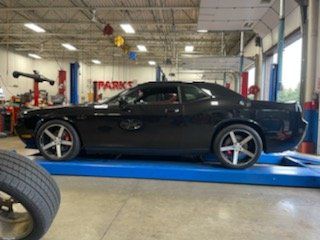Black Dodge Challenger on a blue lift in a garage.