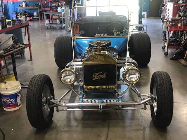 Blue hot rod with chrome accents and large tires inside a garage.