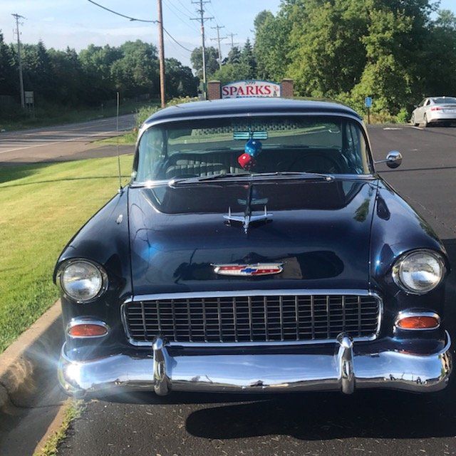 Dark blue classic car parked in front of a building with a 