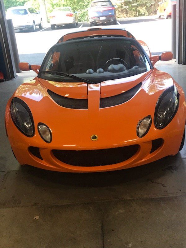 Orange Lotus sports car parked inside a garage.