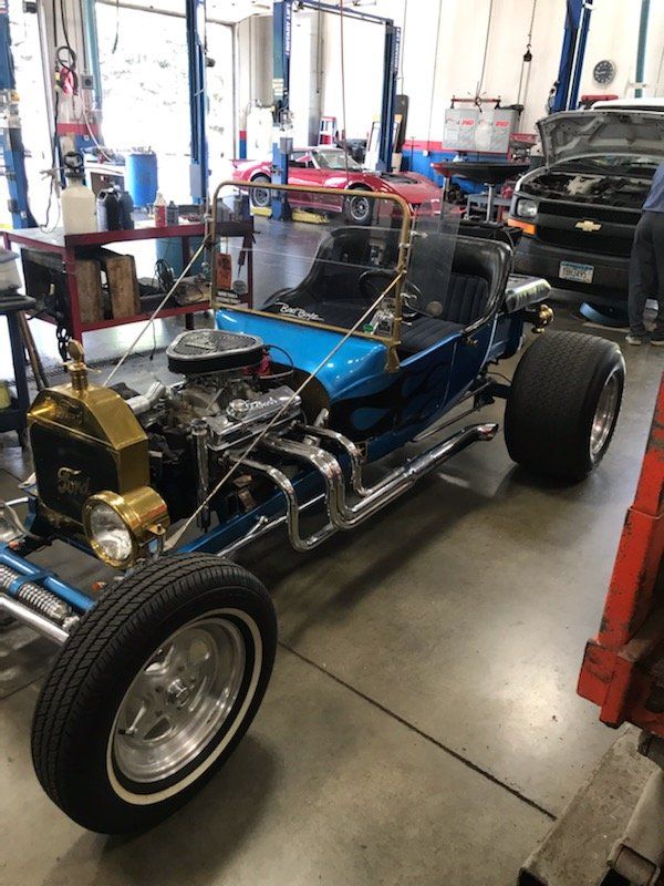 Blue and chrome hot rod in a garage, with large rear tires.