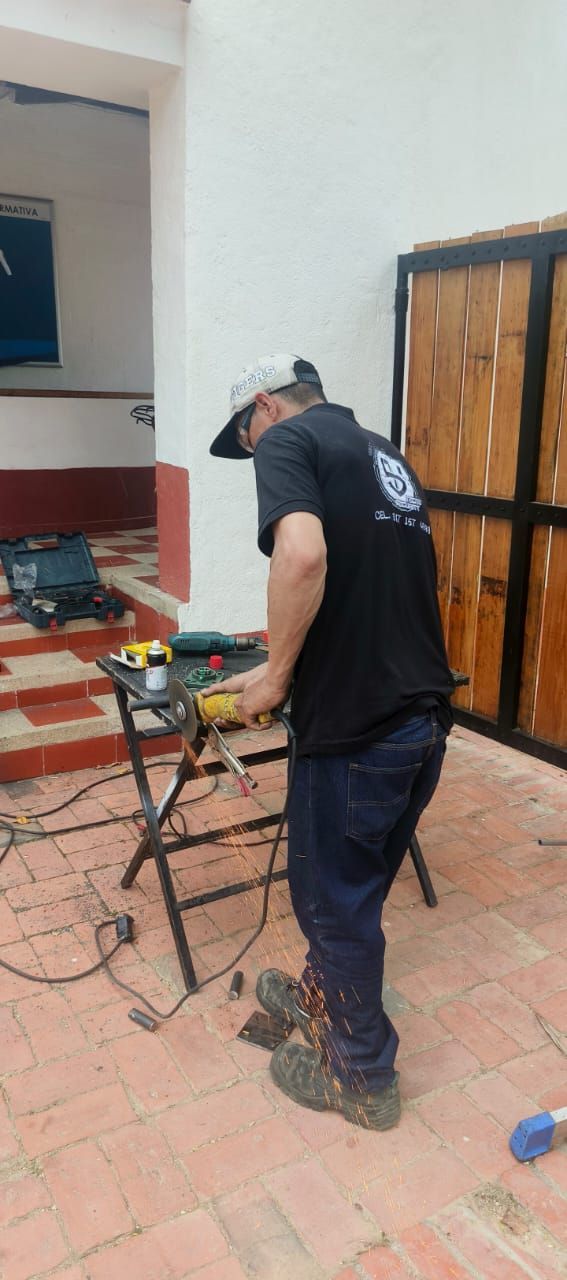 Un trabajador utiliza una herramienta eléctrica en un patio embaldosado junto a la fachada de una casa.