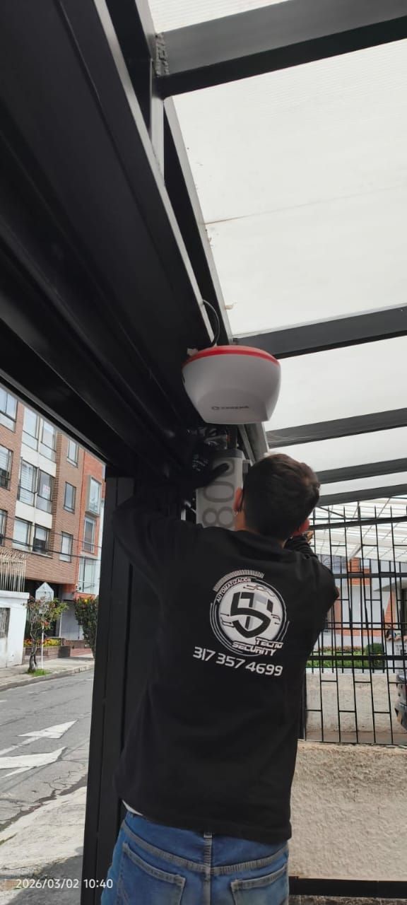 Persona agachada trabajando en una estructura metálica al aire libre en un campo seco.