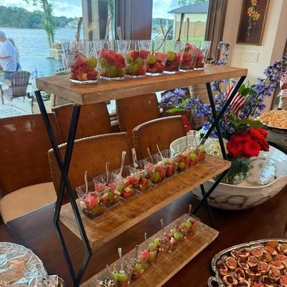 Tiered dessert stand with strawberry parfait cups on a decorated buffet table by a lakeside window.
