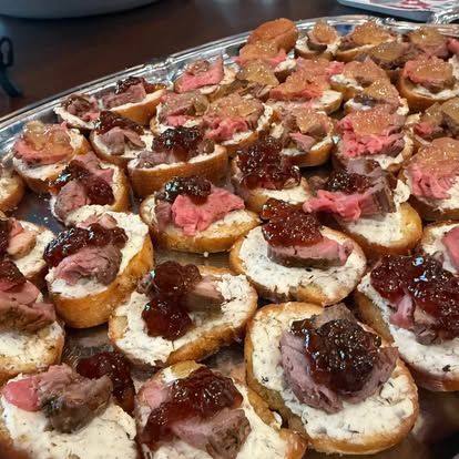 Tray of sliced bread topped with dark jam and pink spread, arranged in neat rows