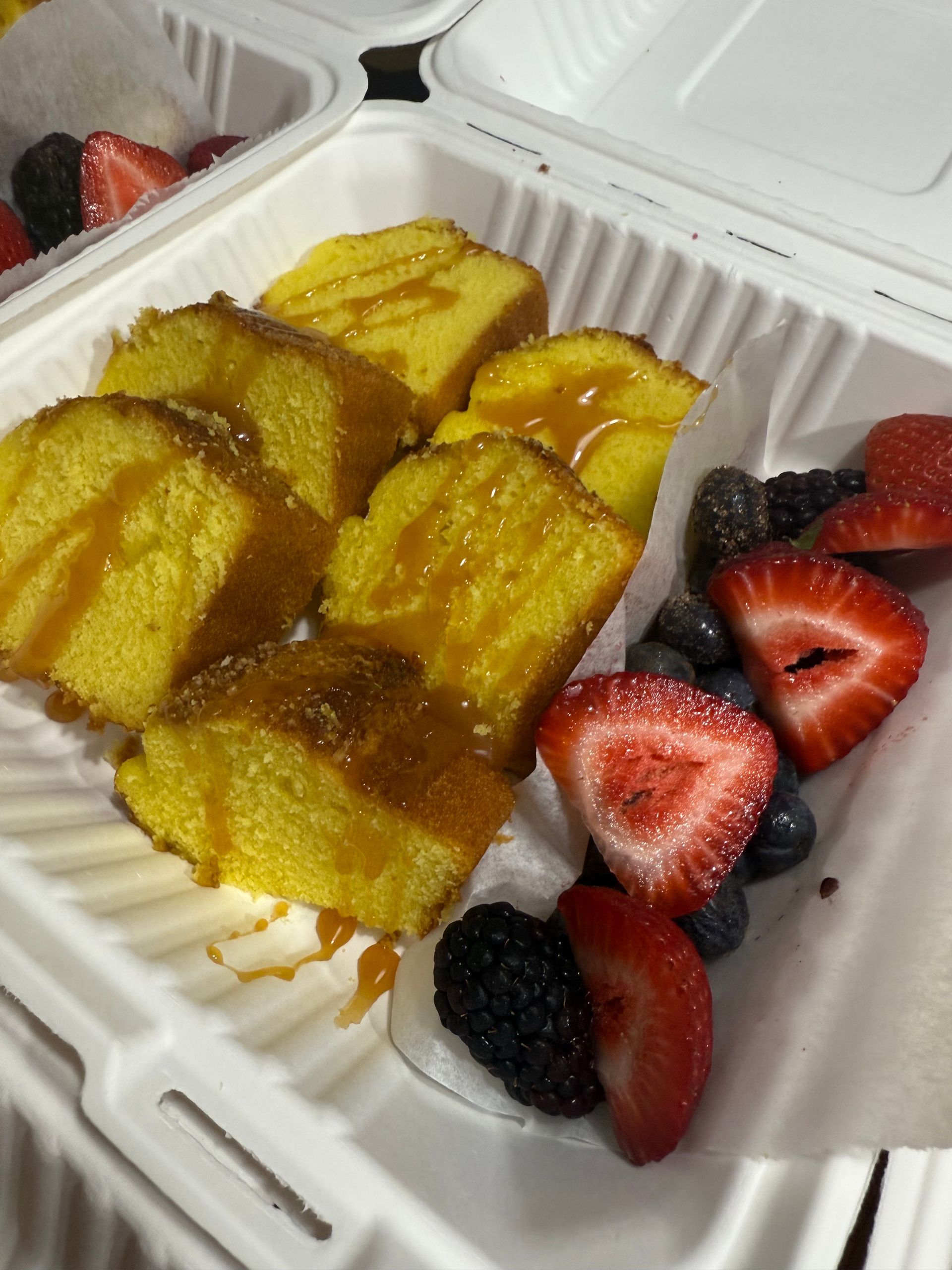 Takeout box with sliced yellow sponge cake and strawberries, raspberries, and blueberries