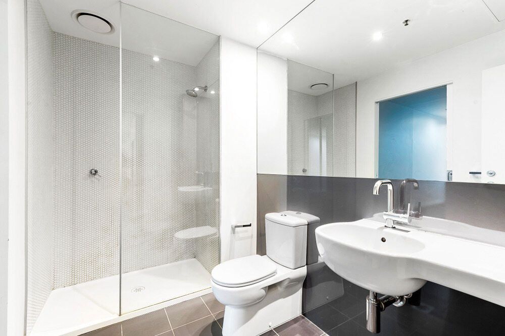 A Bathroom With a Toilet, Sink, Shower and Mirror — Rock Plumbing & Gasfitting In Cannonvale, QLD