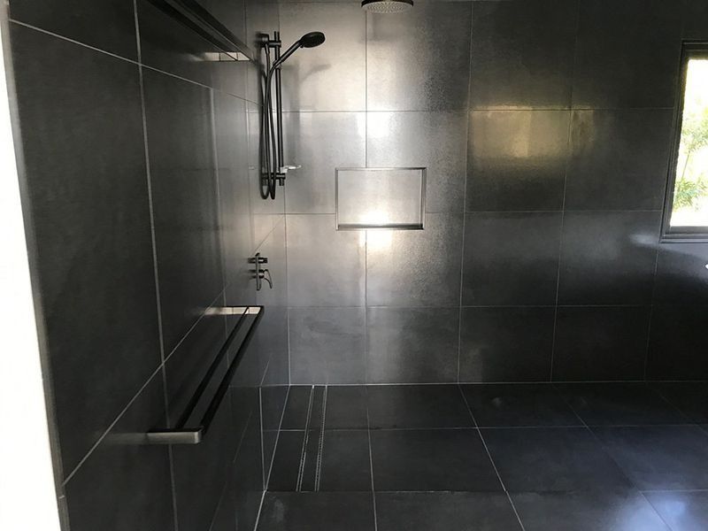 A Bathroom With Black Tiles and a Walk in Shower — Rock Plumbing & Gasfitting In Cannonvale, QLD