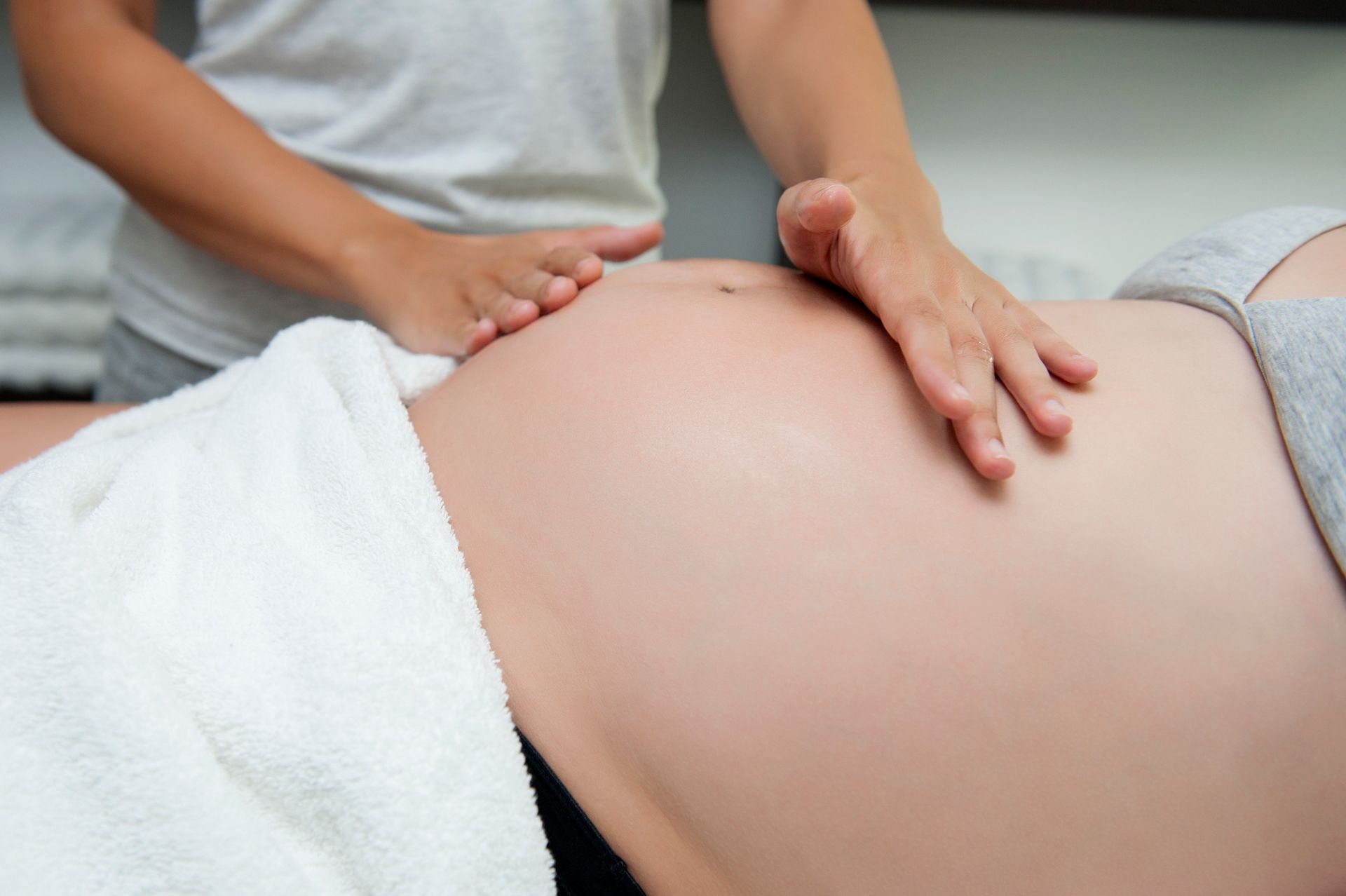 Female massage therapist's hands massaging a pregnant woman's stomach. Female massage therapist's hands massaging a pregnant woman's stomach.