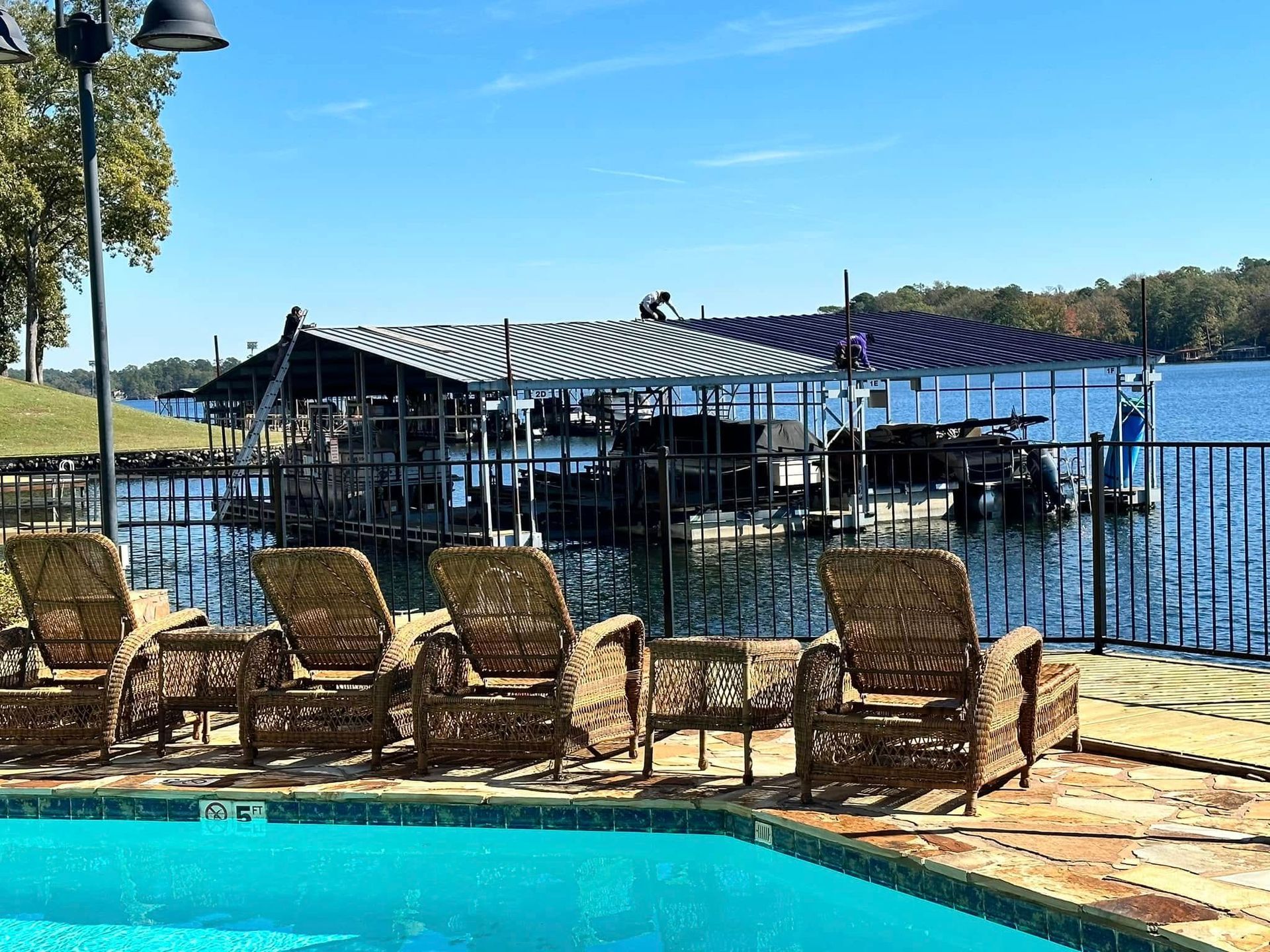 Poolside lounge chairs overlooking a sunny waterfront dock and boats