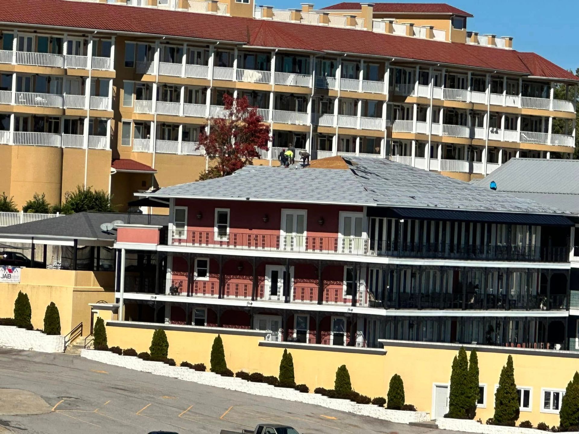 Multi-story resort buildings with balconies and red-tiled roofs in a sunny hillside setting
