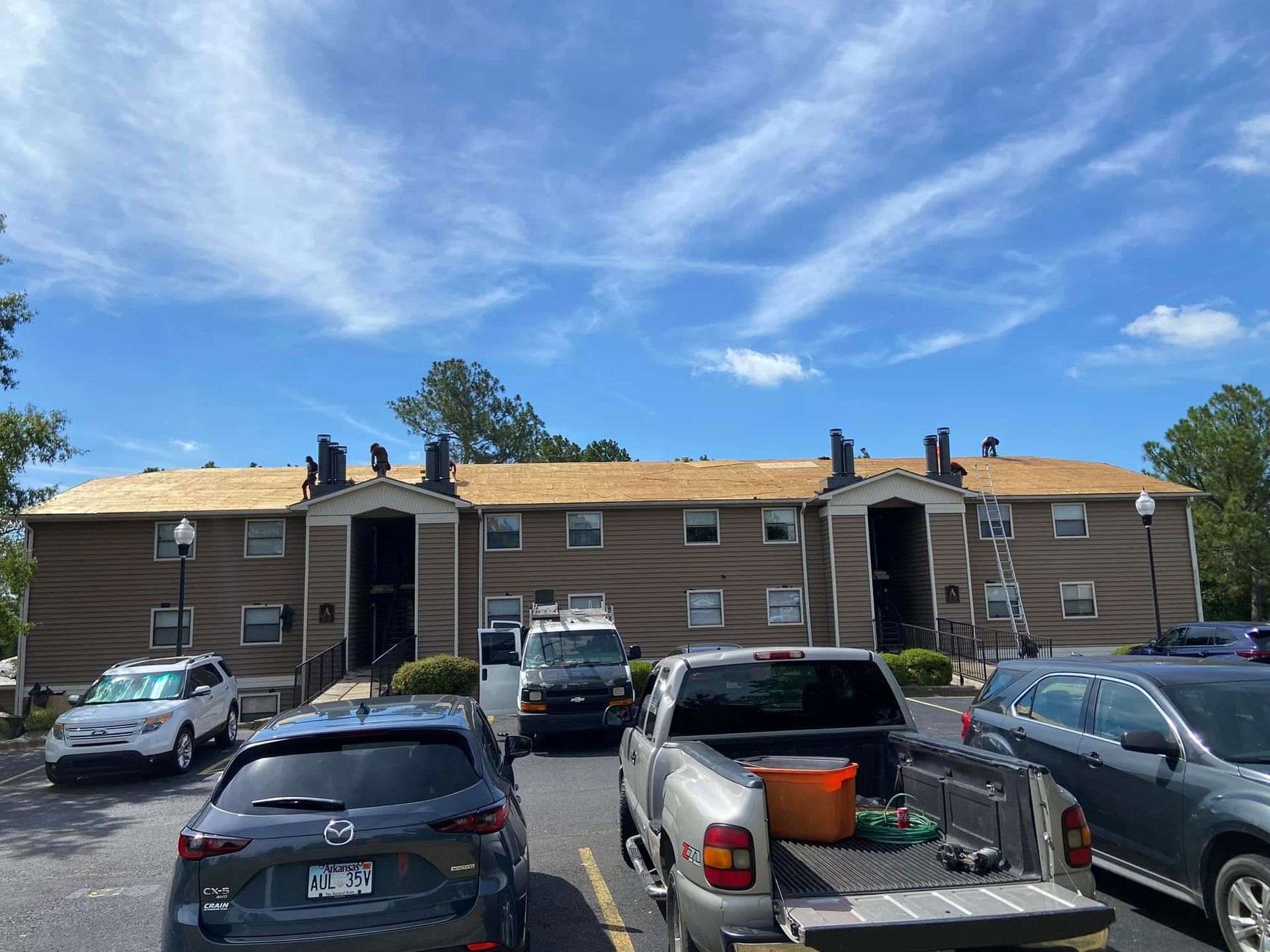 Apartment building parking lot with several parked cars under a bright blue sky
