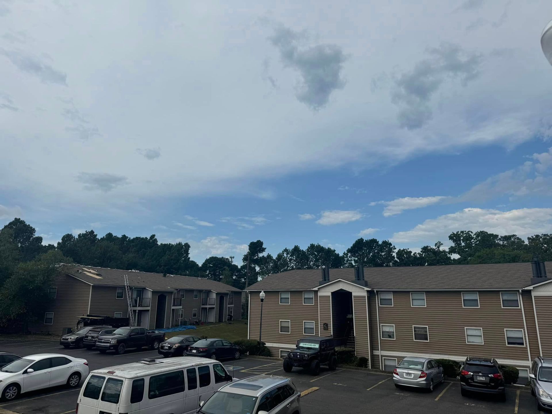 Apartment complex parking lot with cars under a cloudy sky