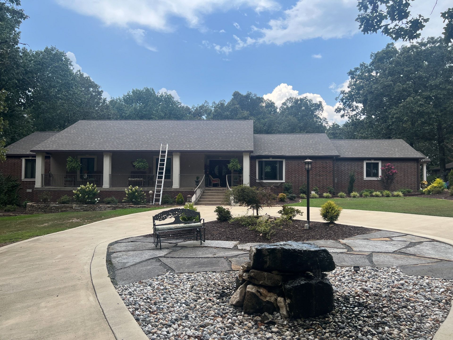 Single-story brick house with curved driveway and landscaped front yard, featuring a fire pit in the foreground