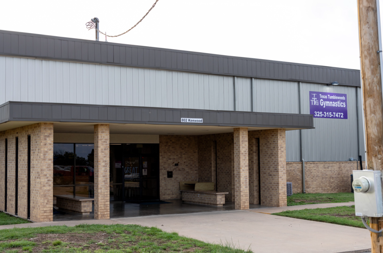 Entrance to a brick building with a metal facade and a purple sign that reads