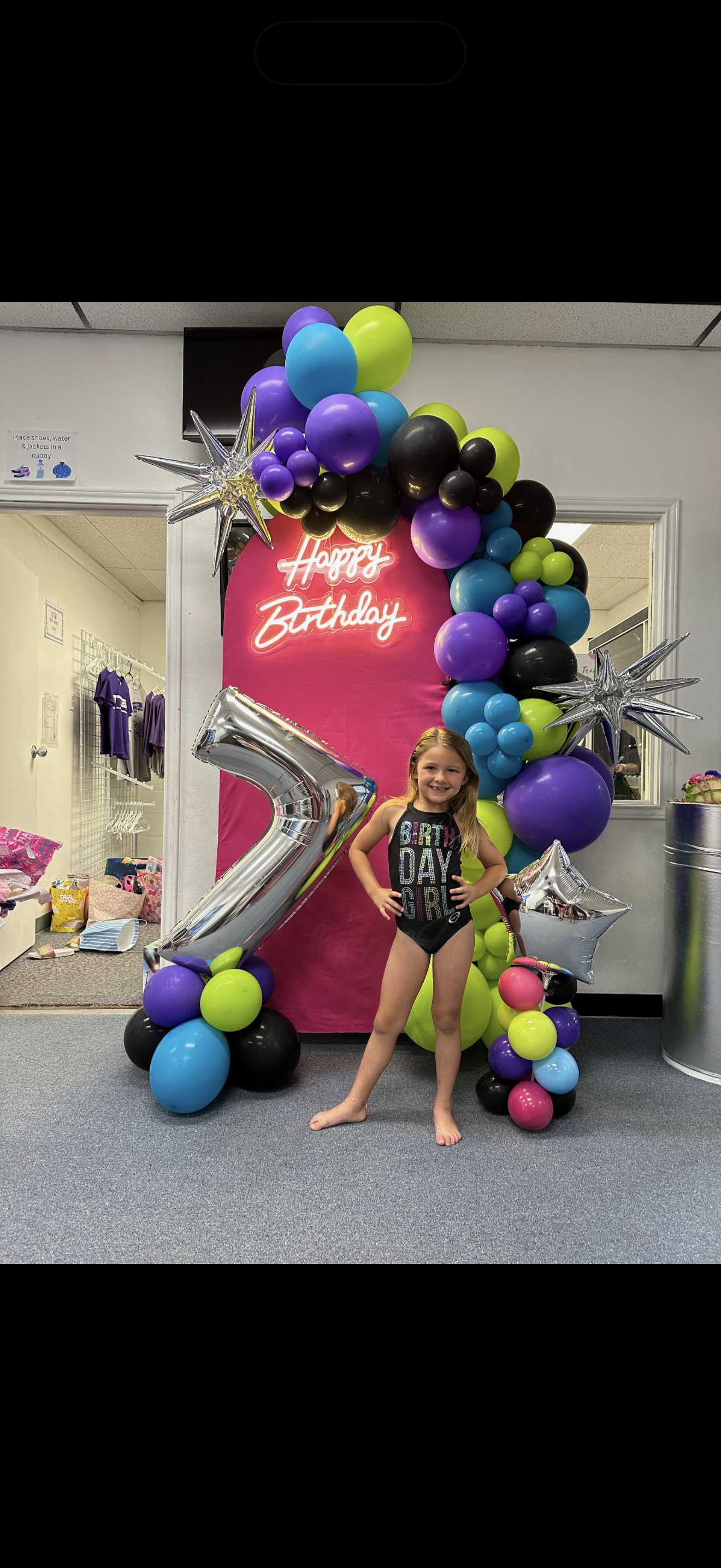 A child poses in front of a neon 