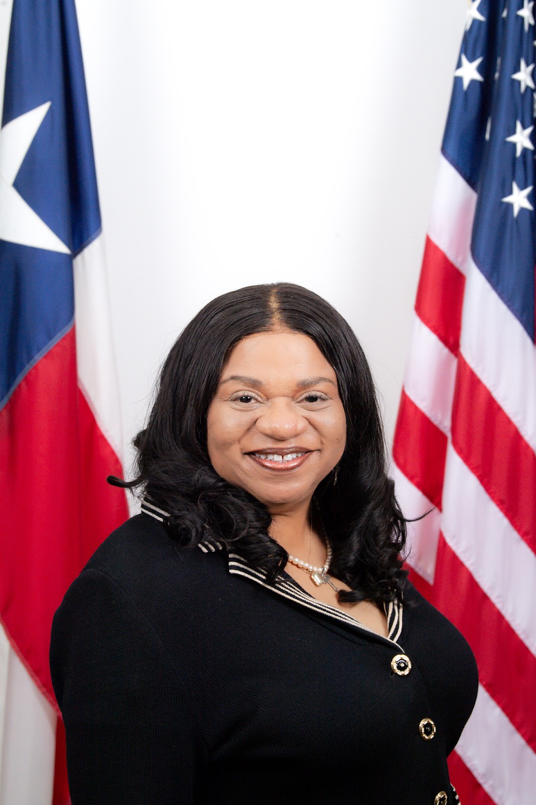 A woman is standing in front of two american flags.
