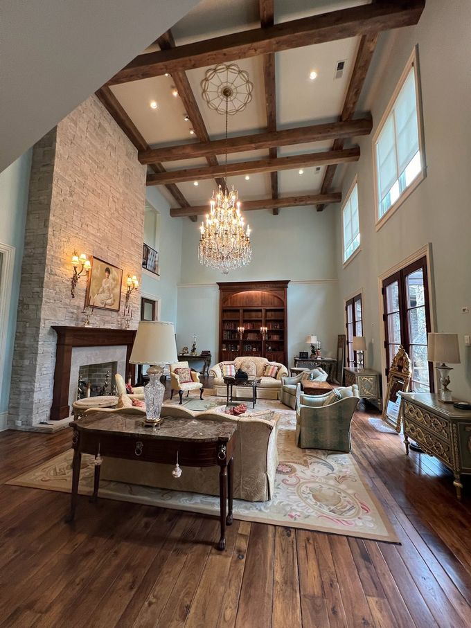 Elegant living room with high ceiling, chandelier, fireplace, and hardwood floors