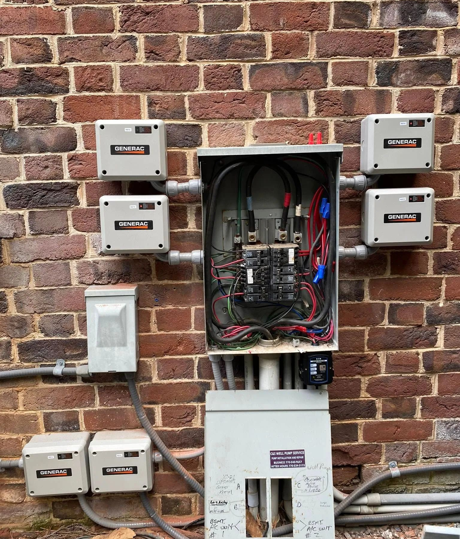 Open electrical breaker boxes and wiring mounted on a brick wall