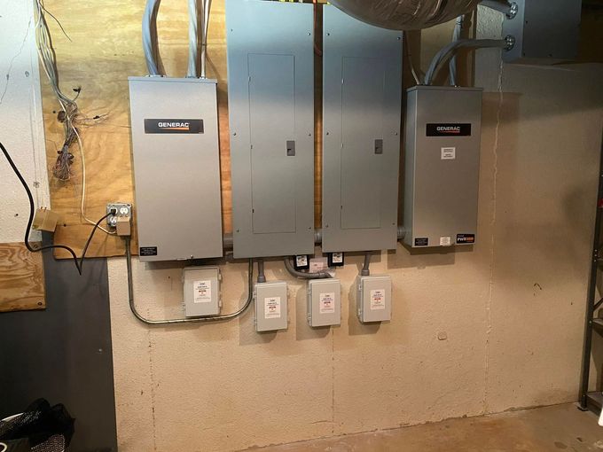 Basement wall with four gray electrical panels and conduit piping.
