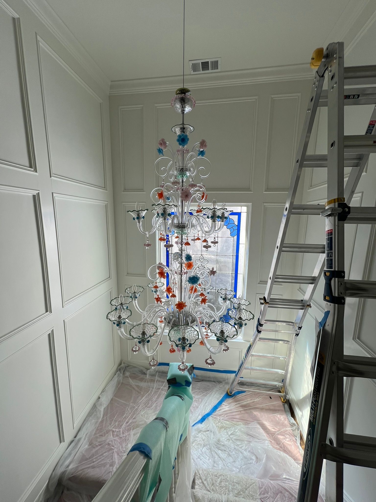 Decorated Christmas tree in a room under construction, with ladders and drywall visible.