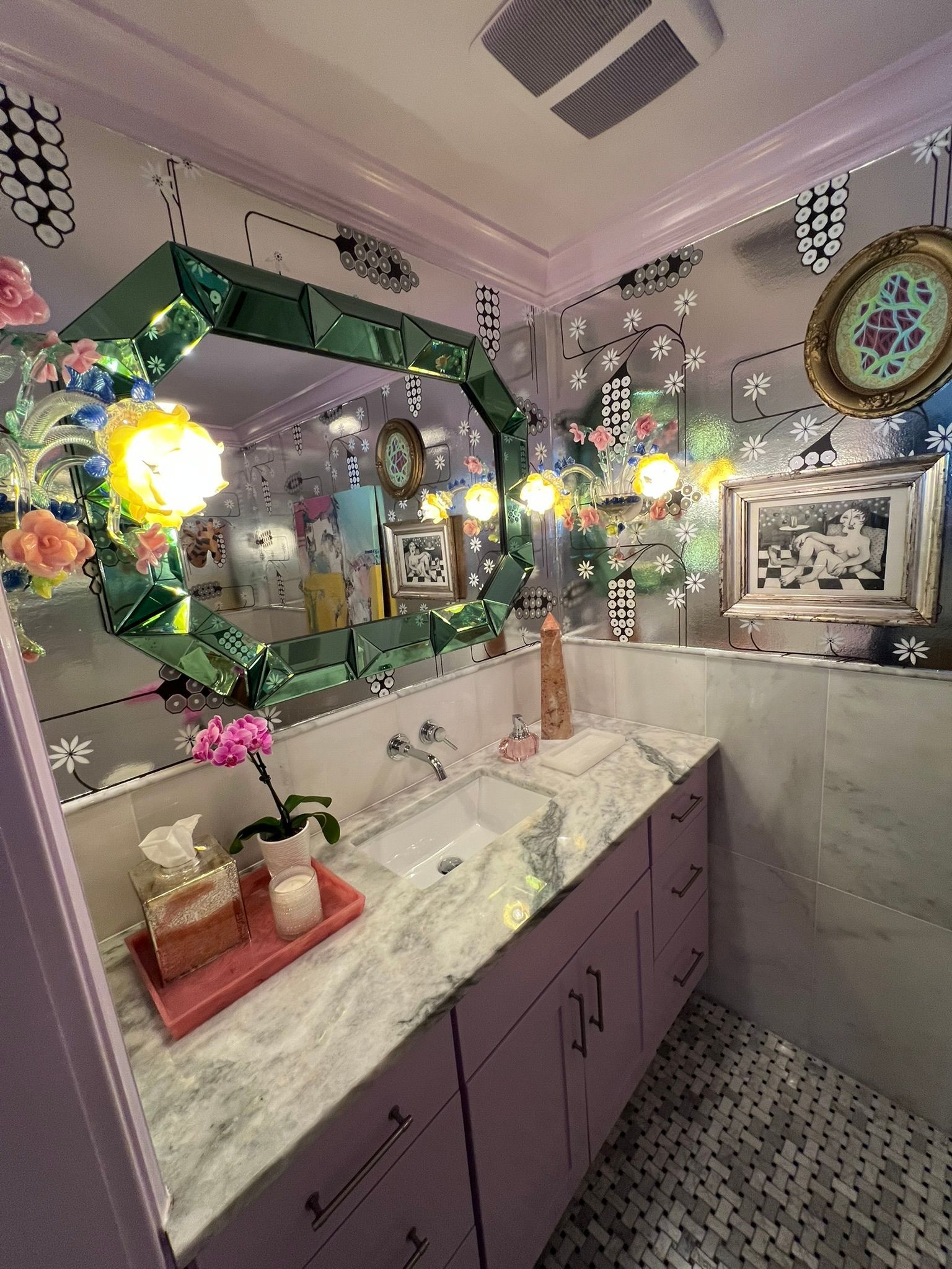 Decorated bathroom with mirror lights, floral accents, white sink, and purple vanity under a sloped ceiling
