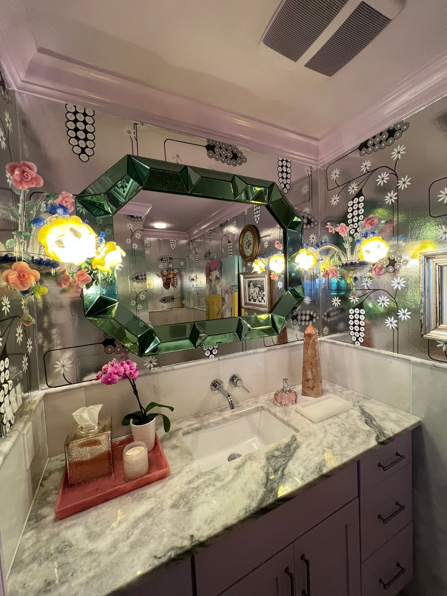 Bathroom vanity with marble countertop, mirrors, green garland, and festive lights reflecting in the mirrors