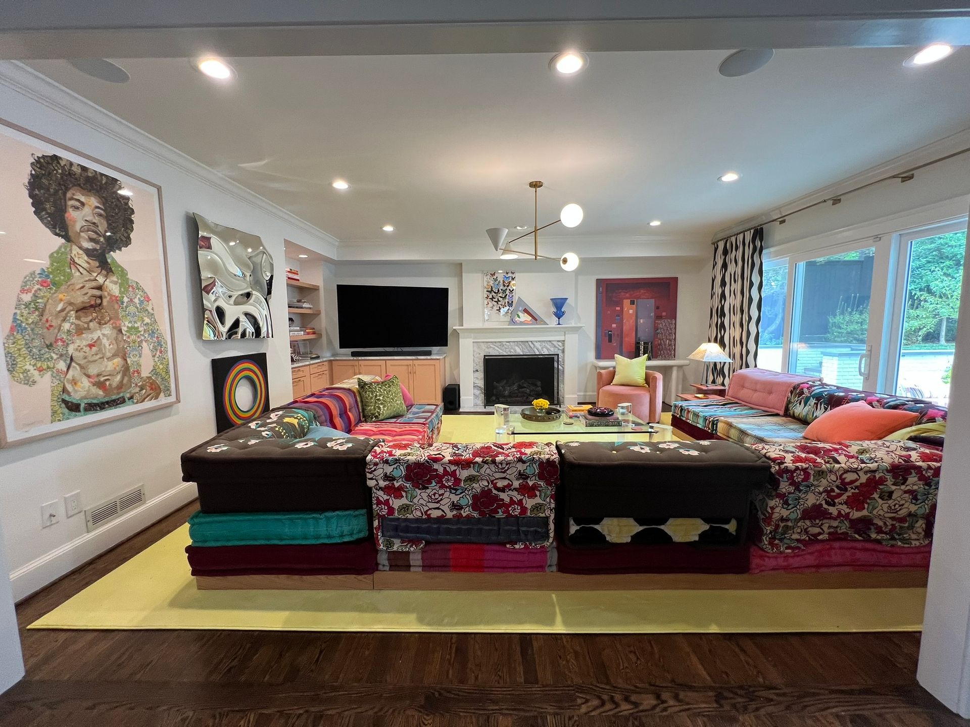Spacious living room with colorful sofas, fireplace, TV, art, and large windows facing a golf course.