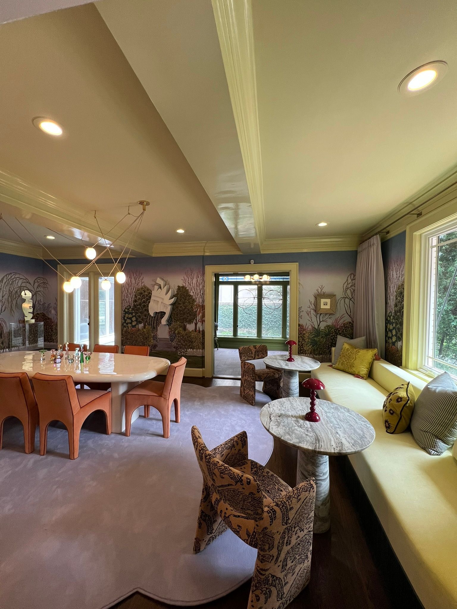 Cozy dining and lounge room with floral sofa, wooden table, leopard chair, and bright windows