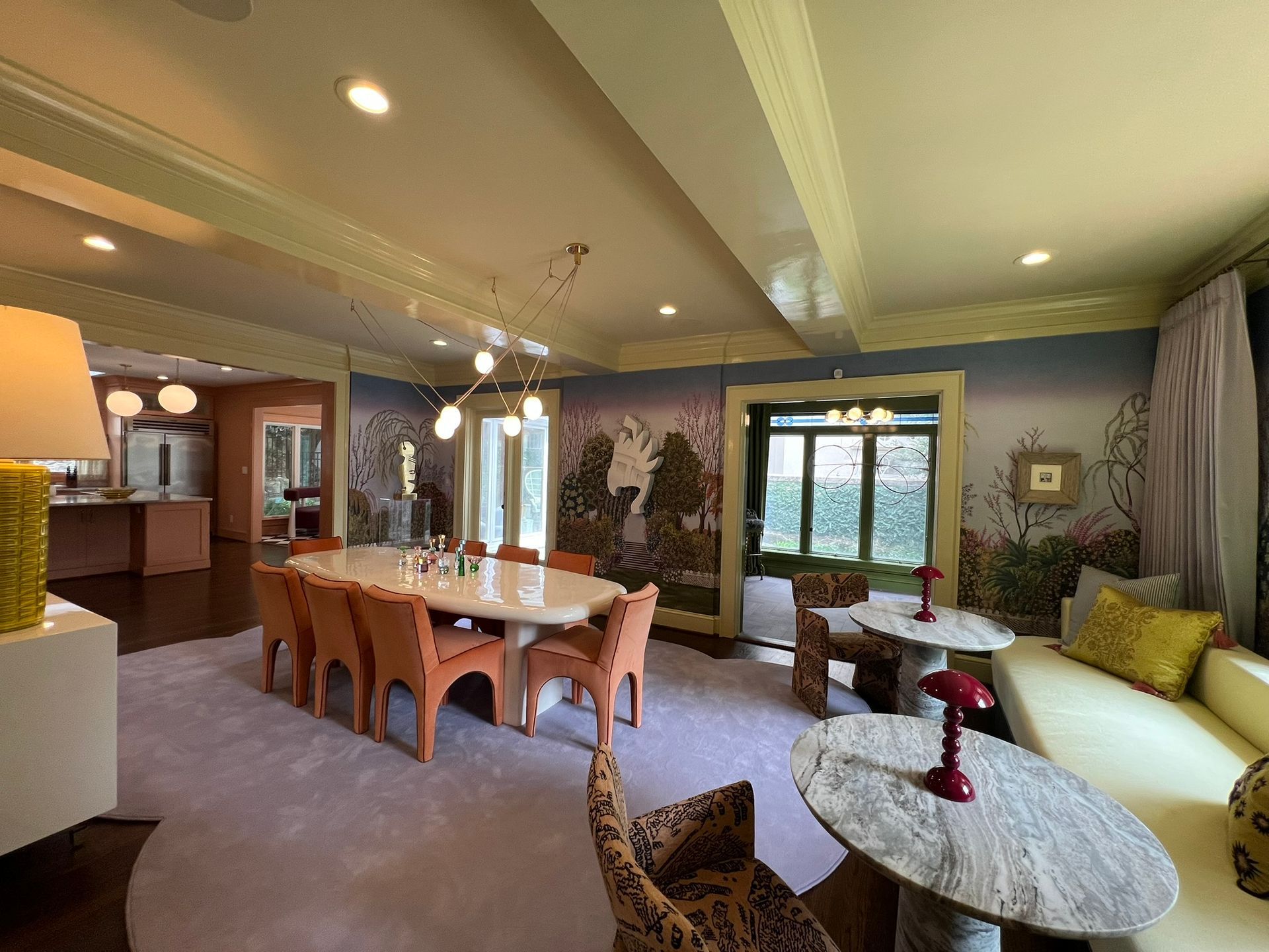 Elegant dining and living room with wood table, sofa, round coffee table, and large windows