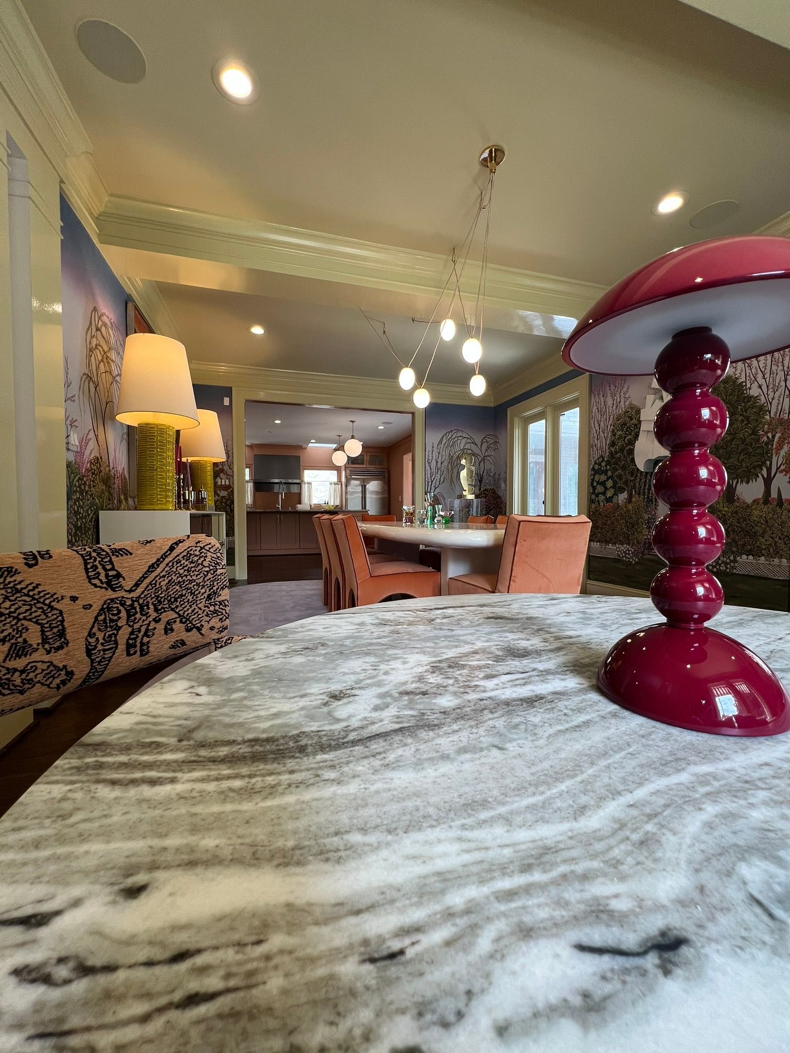 Modern living room with marble table, pink lamp, dining area, and pendant lights
