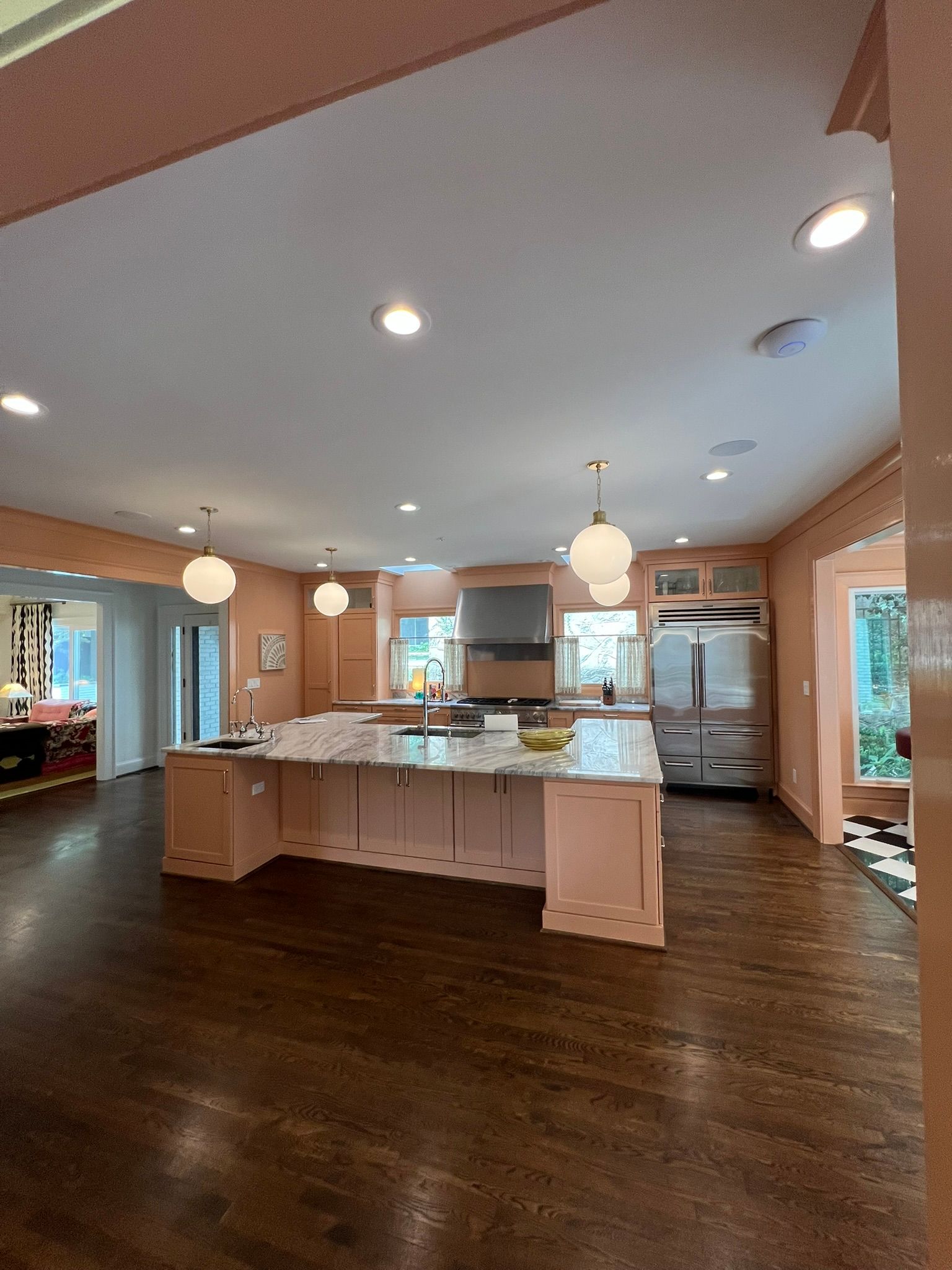 Bright open kitchen with island, white cabinets, dark wood floors, and pendant lights